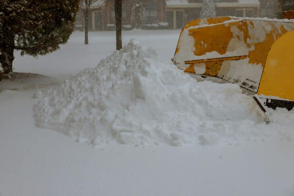 Truck With Snowplough Cleaning Road by Removing Snow from Road After Winter Blizzard